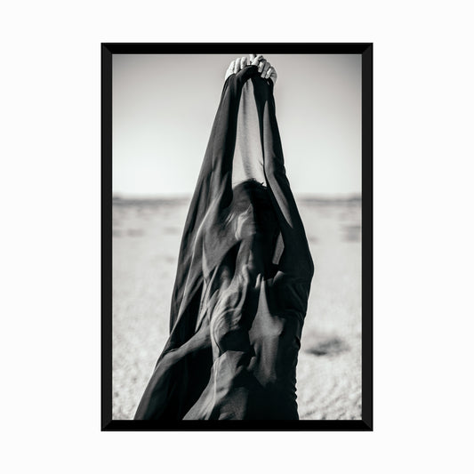 Artistic abstract portrait of woman covered with black fabric in desert